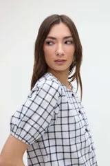 Camisa a cuadros de manga corta abullonada y cuello redondo, con cierre frontal de botones.