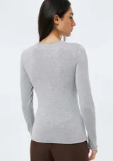 Blusa de punto gris claro melange, de tejido liviano, corte ajustado al cuerpo, cuello redondo y manga larga.
