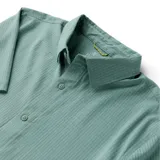 Camisa de manga corta color verde claro, con cuello camisero y cierre frontal de botones.