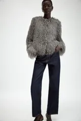 Chaqueta de cuello redondo y manga larga, confeccionada con textura de flecos en toda la prenda. Presenta cierre frontal con ganchos ocultos y un diseño corto.