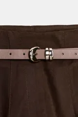 Pantalón tobillero de tiro medio, color azul marino, con bolsillos delanteros y cierre frontal con cremallera, botón y gancho. Incluye un cinturón fino de color marrón con hebilla metálica.