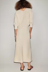 Vestido midi de punto color marfil con escote en V, mangas largas de sisa ancha, cintura entallada y falda de corte evasé.