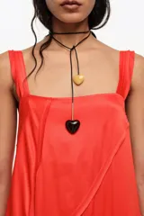 Vestido midi de línea A con vuelo color rojo, confeccionado en mezcla de viscosa y lyocell, con escote cuadrado, tirantes anchos y tiras diagonales decorativas.