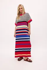 Vestido largo tejido a rayas horizontales en tonos beige, marrón, negro y rojo. Tiene cuello redondo, mangas cortas y tajos laterales.