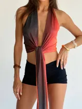 Top halter de tela brillante con efecto degradado que va del negro al naranja rojizo, anudado al frente.