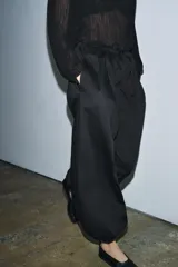 Pantalón negro de tiro medio con cintura ajustable mediante cordones y bajo abullonado con puño elástico.