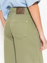 Pantalón de corte relajado color verde oliva, confeccionado en algodón. Presenta un diseño de cinco bolsillos estilo jeanero, tiro alto, pierna ancha y largo al tobillo.