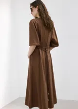 Vestido midi marrón de corte recto, con cuello redondo, mangas tres cuartos y detalle de cinturón fino en la cintura.