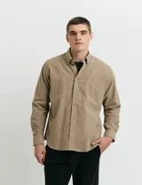Camisa de franela lisa con cuello button-down, manga larga, botones al tono y bolsillo frontal en el pecho.