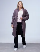 Campera larga de sherpa color negro, con cierre frontal y bolsillos laterales.