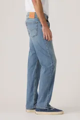Pantalón de jean corte regular, con diseño clásico de cinco bolsillos, cierre de botón y cremallera, en tono azul medio con acabado desgastado.