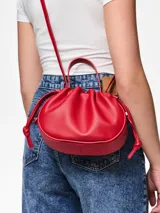 Bolso de mano tipo saco o 'balloon' de cuero sintético color rojo vibrante, con cordón ajustable en la parte superior y asas cortas.
