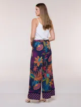 Pantalón pull on largo de caída fluida, cintura alta con pretina trasera elastizada, pierna de corte ancho tipo palazzo y detalle de guarda geométrica sobre el ruedo inferior, con estampado floral multicolor sobre base azul.