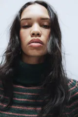 Jersey de punto con cuello subido y manga corta, diseño a rayas horizontales en tonos verde oscuro, negro y rosado.