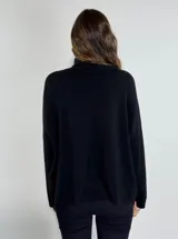 Sweater negro de cuello alto con diseño asimétrico, confeccionado en tejido de punto con detalle de encaje floral aplicado en el frente y el ruedo.