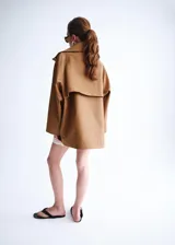 Chaqueta oversize color tostado con cuello embudo, manga larga, bolsillos laterales y bolsillos de parche con solapa. Cuenta con cierre delantero de cremallera y botones ocultos bajo tapeta, y forro interior.