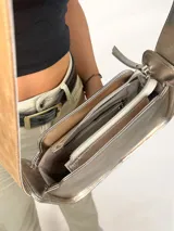 Cartera baguette dorada de cuero genuino, con asa reversible.