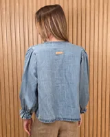 Camisa color beige de lino con mangas abullonadas tres cuartos y cierre frontal mediante múltiples lazos para atar.