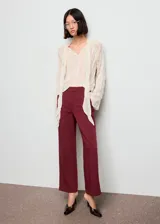 Pantalón de vestir color bordó, de tiro alto y diseño recto, con bolsillos laterales y cierre oculto con botón, gancho y cremallera.