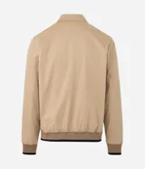 Campera tipo bomber de sarga color beige, con cuello inglés, cierre frontal de cremallera y puños y cintura ajustados con elástico en tono contrastante.