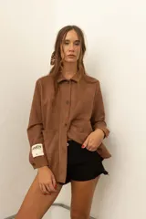 Camisa marrón de corte recto con botones y bolsillos frontales.