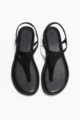 Sandalias planas de dedo color negro, con diseño minimalista y tira fina en el empeine con sujeción trasera elástica.