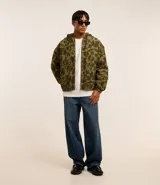 Campera con capucha y cierre frontal, confeccionada en sarga con estampado camuflado. Tiene manga larga con sisa desplazada, puños ajustados, bolsillo canguro y bajo con elástico.