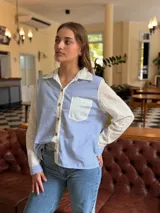 Camisa de corte clásico con diseño combinado, presenta cuerpo a rayas verticales en azul y blanco, con mangas largas y cuello en tela broderie blanca con detalles calados. Incluye bolsillo frontal en broderie y cierre central con botones.