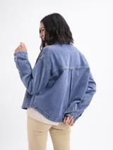 Campera de jean azul con corte holgado, cuello clásico, cierre frontal con botones y bolsillos delanteros amplios.