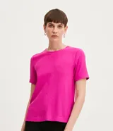 Blusa blanca de poliéster con cuello redondo, mangas cortas, cierre trasero en forma de gota, pequeñas aberturas laterales y acabados en pespuntes en las mangas y el cuello.