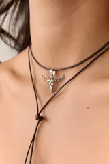 Collar con dije de acero quirúrgico en forma de cráneo de toro, montado sobre un cordón marrón.