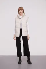 Chaleco acolchado color marfil con cuello alto y cierre frontal con botones a presión.