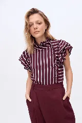 Remera bordó con rayas verticales blancas, de manga corta con volados, cuello alto fruncido y cierre lateral de botones con detalles de volados.