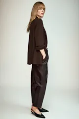 Blazer negro de cuello solapa con hombreras, manga por debajo del codo con drapeado y falsos bolsillos de vivo en el delantero. Cuenta con forro interior a tono y cierre frontal con un botón.