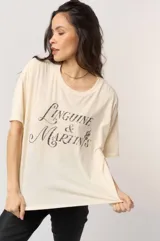 Remera de algodón color crema, corte oversize y cuello redondo. Presenta un estampado frontal en tipografía cursiva oscura con el texto "Linguine & Martin's" y un pequeño detalle de cereza.