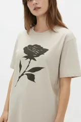 Remera de manga corta color blanco, de corte holgado con cuello redondo a la base y estampado frontal en tono bordó de un gato y un ovni en un paisaje desértico.
