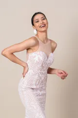 Vestido largo de tul color nude, con bordados blancos de diseño floral. Presenta escote redondo, corte ajustado y falda con vuelo.
