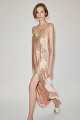 Vestido largo tipo lencero de Zara Woman Collection, confeccionado en tejido satinado color rosado con escote en pico y tirantes finos. Presenta detalles de aplicaciones de encaje a contraste y bajo asimétrico.