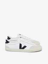 Zapatillas Veja modelo Volley, color blanco con logo lateral en forma de "V" color negro y detalles en azul marino en el talón. Fabricadas con algodón orgánico, gamuza y cuero.