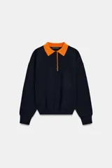 Jersey de punto de manga larga con cuello tipo polo en color naranja a contraste. Presenta cierre frontal con botones y diseño de corte holgado.