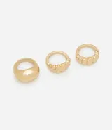 Set de tres anillos dorados de metal reciclado. Uno es liso y abombado, otro tiene textura de líneas diagonales y el tercero tiene textura de líneas verticales.