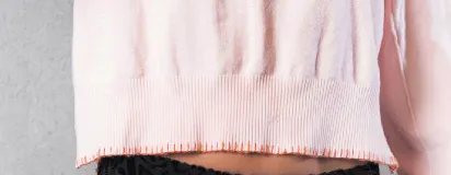 Sweater de punto color rosa claro, con cuello redondo a la base, mangas largas y puños acanalados. Presenta detalles de terminación a mano en contraste en el cuello, puños y ruedo.