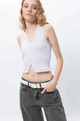 Crop top blanco de algodón, sin mangas, con cuello halter y abertura en el frente.