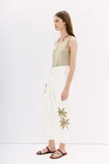 Pantalón blanco de algodón, tiro alto con corte paper bag y lazo a tono en la cintura. Presenta bordado de palmeras con lentejuelas y piedras en el lateral de la pierna.