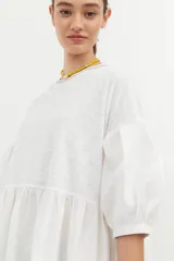 Vestido corto blanco de algodón con lurex, corte evasé, mangas cortas abullonadas y cuello redondo con ribete amarillo.