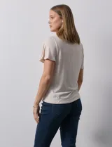 Remera color beige de tejido melange con escote en V y aplique de crochet en el frente.