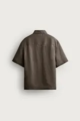 Camisa negra de manga corta, confeccionada en lino con corte relaxed fit, cuello bowling y cierre frontal de botonadura.