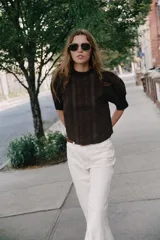 Blusa blanca de cuello alto con detalles de puntilla, manga corta abullonada y cierre posterior con botón.