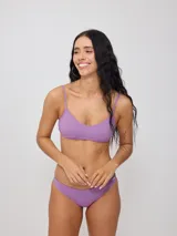 Top de bikini con tirantes finos y escote redondo, confeccionado en poliamida con elastano, con estampado tropical en tonos verdes, celestes y salmón sobre fondo negro.