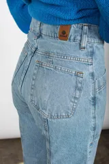 Jean de tiro alto confeccionado en denim de algodón, con diseño de piernas amplias y rectas, cuatro bolsillos, cierre de botón y detalles de ribetes al frente.